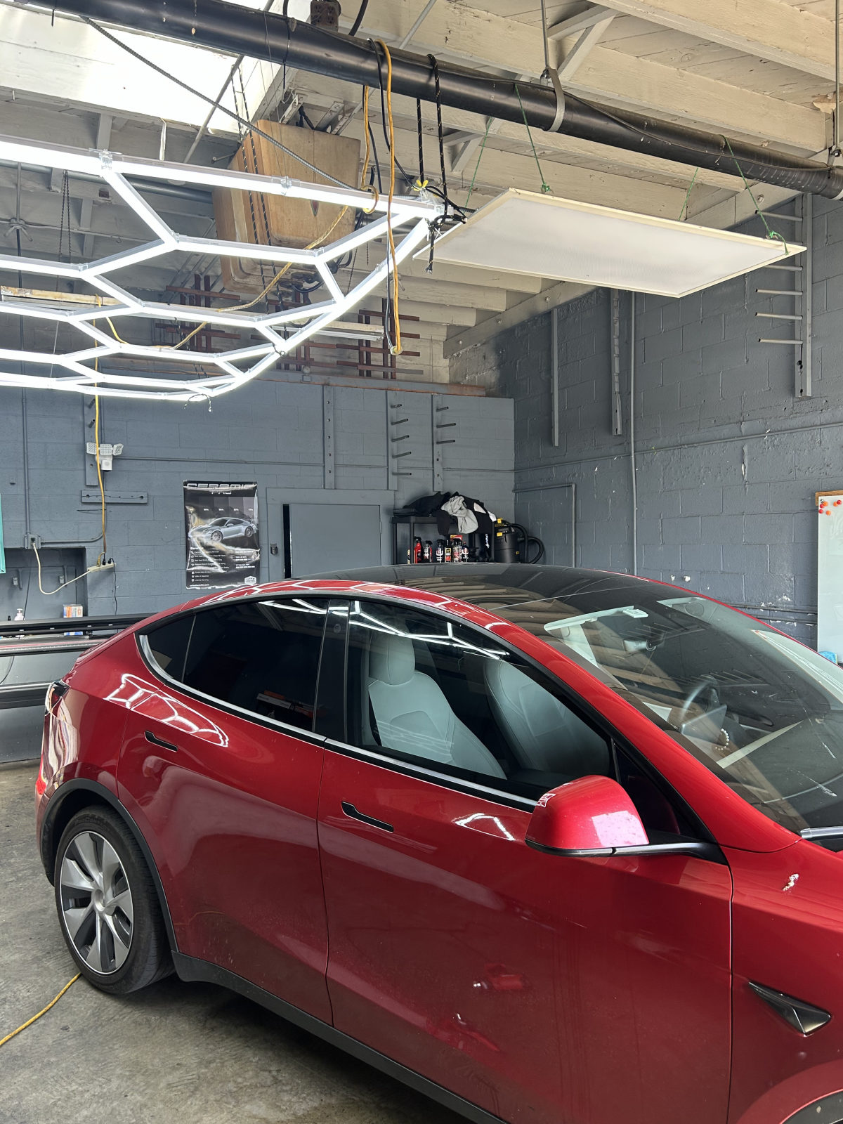 Freshly tinted red Tesla Model Y under the SOS Tints LED bay